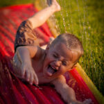 image of child playing with outdoor water toys, a slip n' slide.