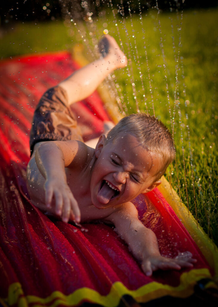 image of child playing with outdoor water toys, a slip n' slide.