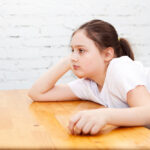 image of 10 year old with elbow on a table, looking bored. In need of screen free activities for 10 year olds.