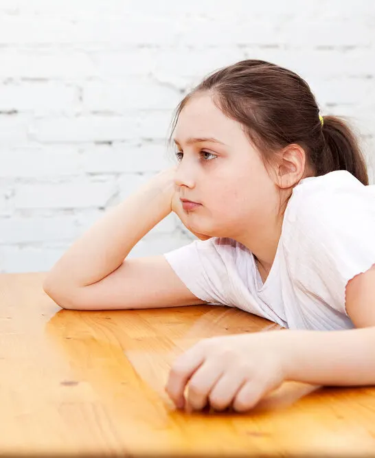 image of 10 year old with elbow on a table, looking bored. In need of screen free activities for 10 year olds.