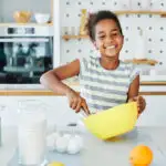 image of smiling Black girl cooking for the kids cooking shows post.
