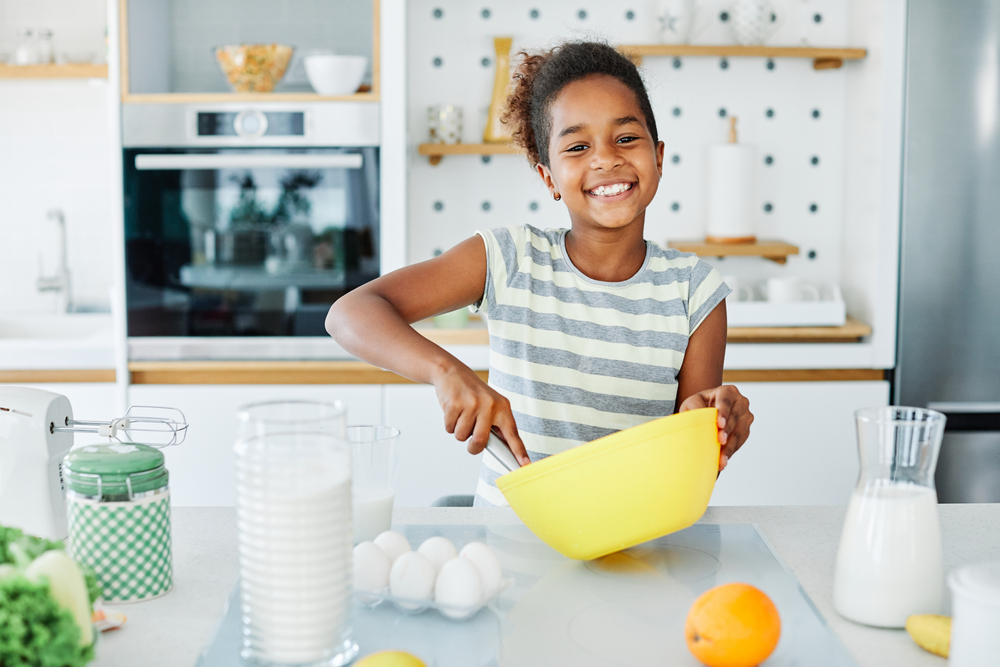 image of smiling Black girl cooking for the kids cooking shows post.