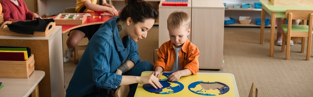 image of montessori teacher showing puzzle maps to young child in a screen free school.